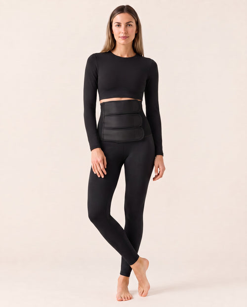 Model wearing MADRE Restore Legging high-waisted postpartum leggings with three-strap adjustable belly wrap and a black long-sleeve top
